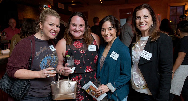 A photo of four women, each wearing a label tag on their clothes.