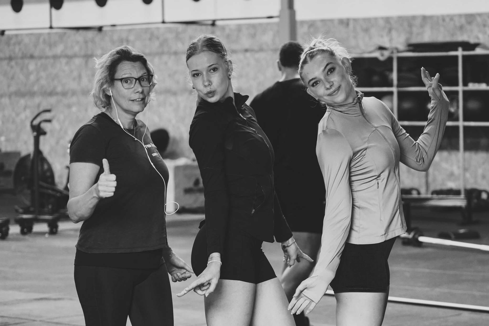 black and white photo of three women standing in a row looking at the camera showing a peace sign