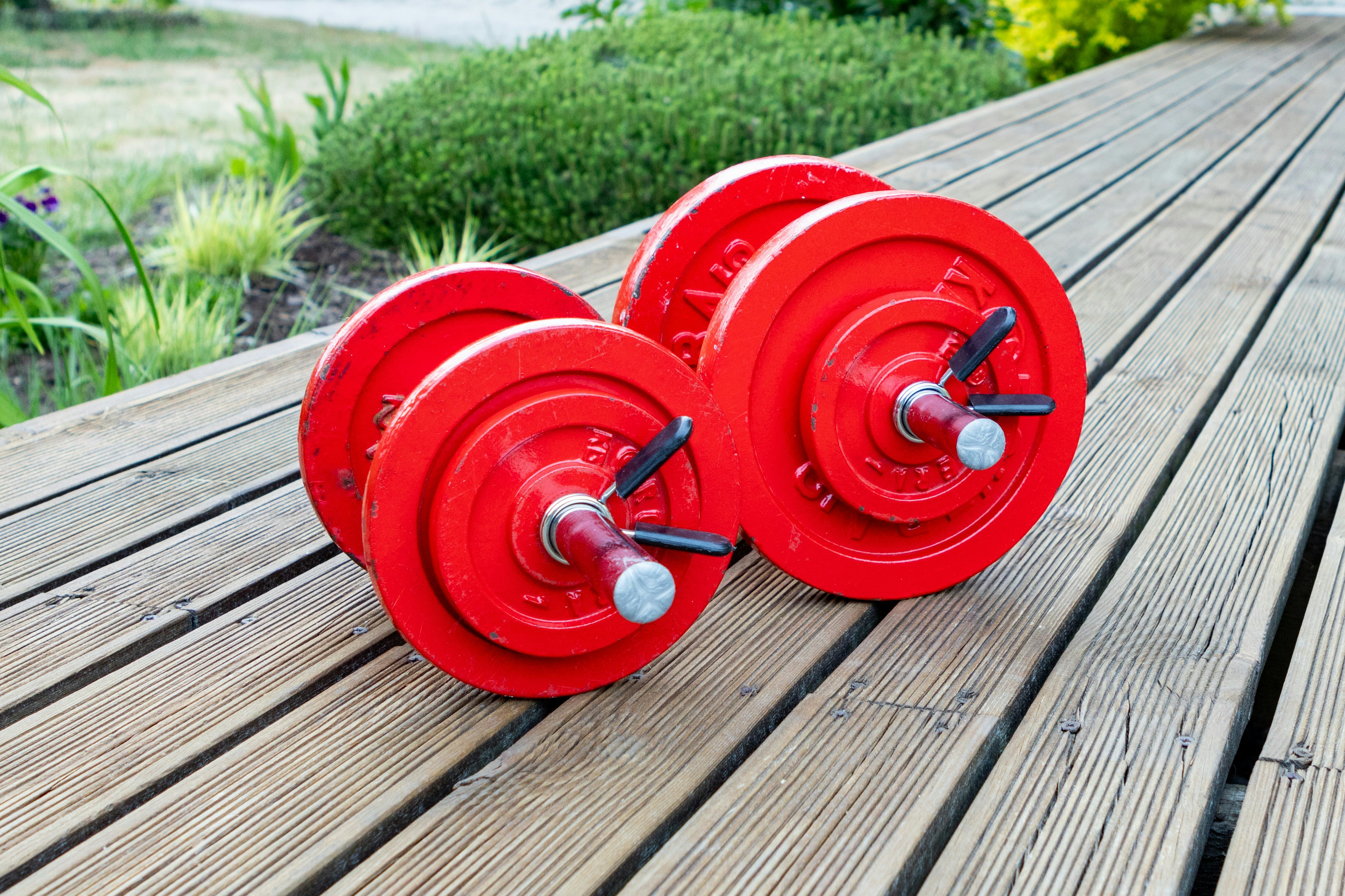 two red dumbbells sitting on a wooden table