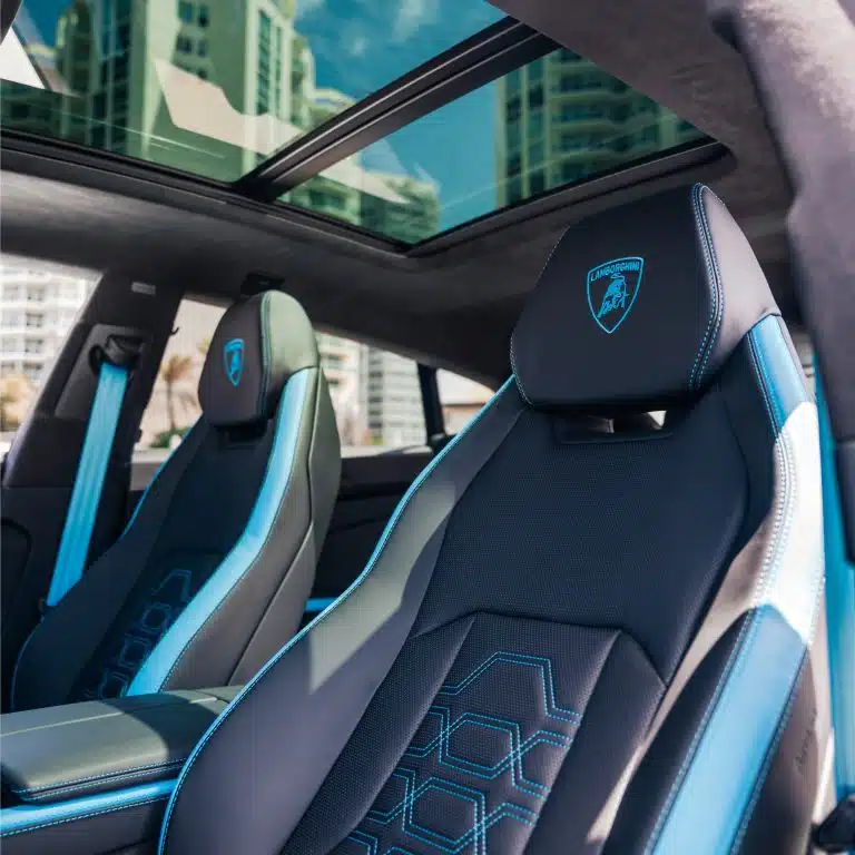 Interior shot of the Lamborghini Urus SE's front passenger seat and panoramic sunroof, highlighting the luxurious black and blue leather upholstery.