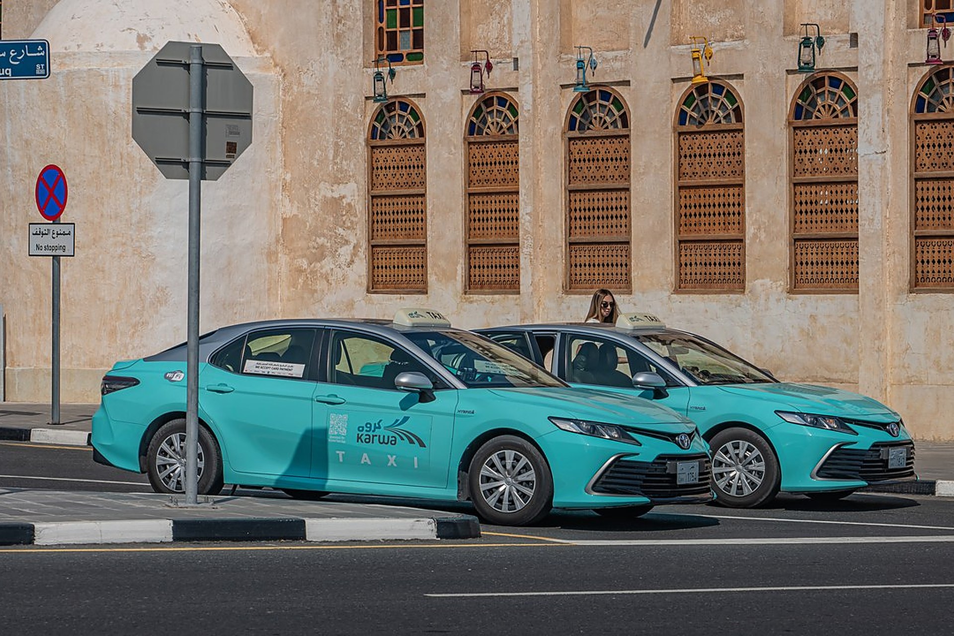 Deux taxis Karwa turquoise garés devant une façade traditionnelle de Doha, le taxi national que l'on commande depuis l'application
