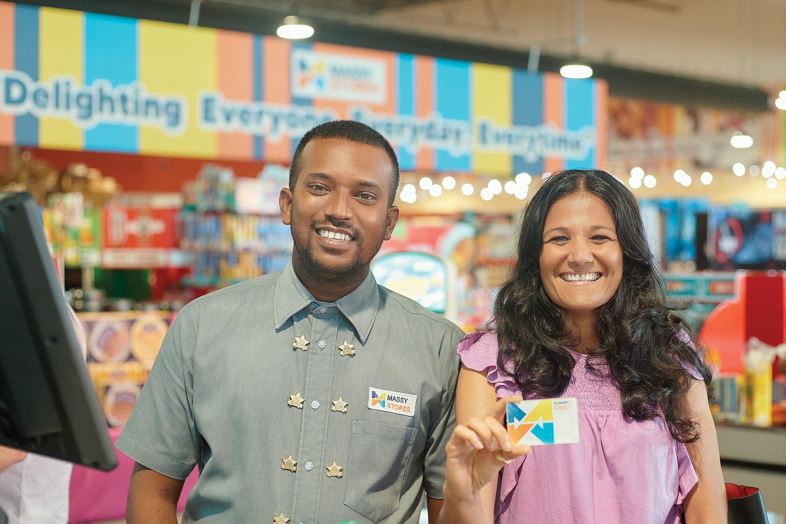 Smiling Massy store employee and Massy customer showing her loyalty card