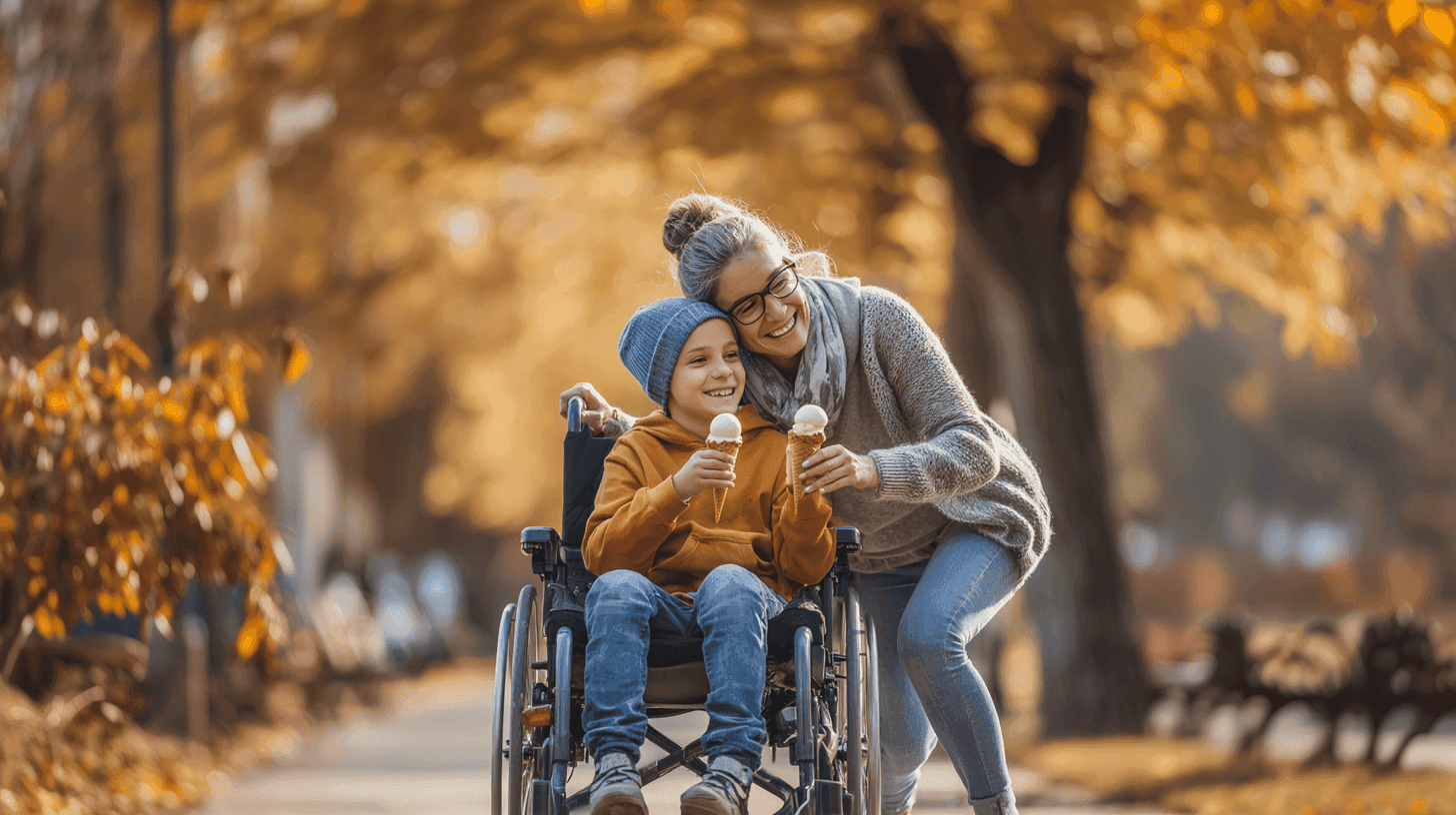 A caregiver helps a person in a wheelchair through a park filled with autumn leaves, both smiling warmly.