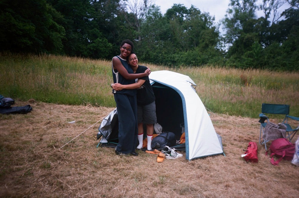 Two people hug outside a tent in a field