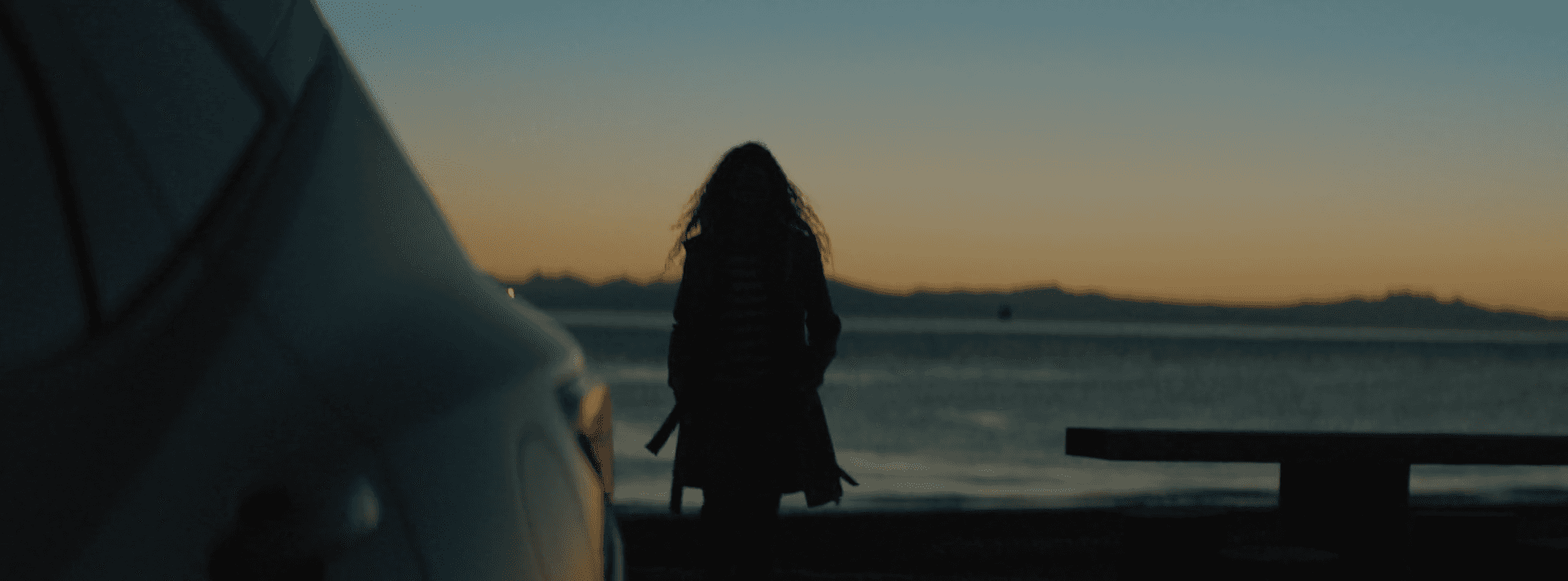 A person walks down a dimly lit alley at night.