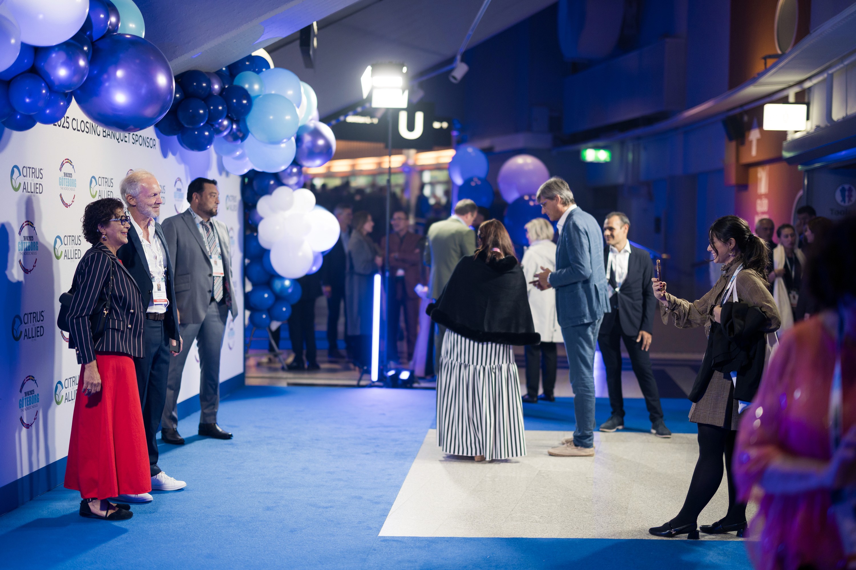 Uppklädda människor står framför en fotovägg med ballonger