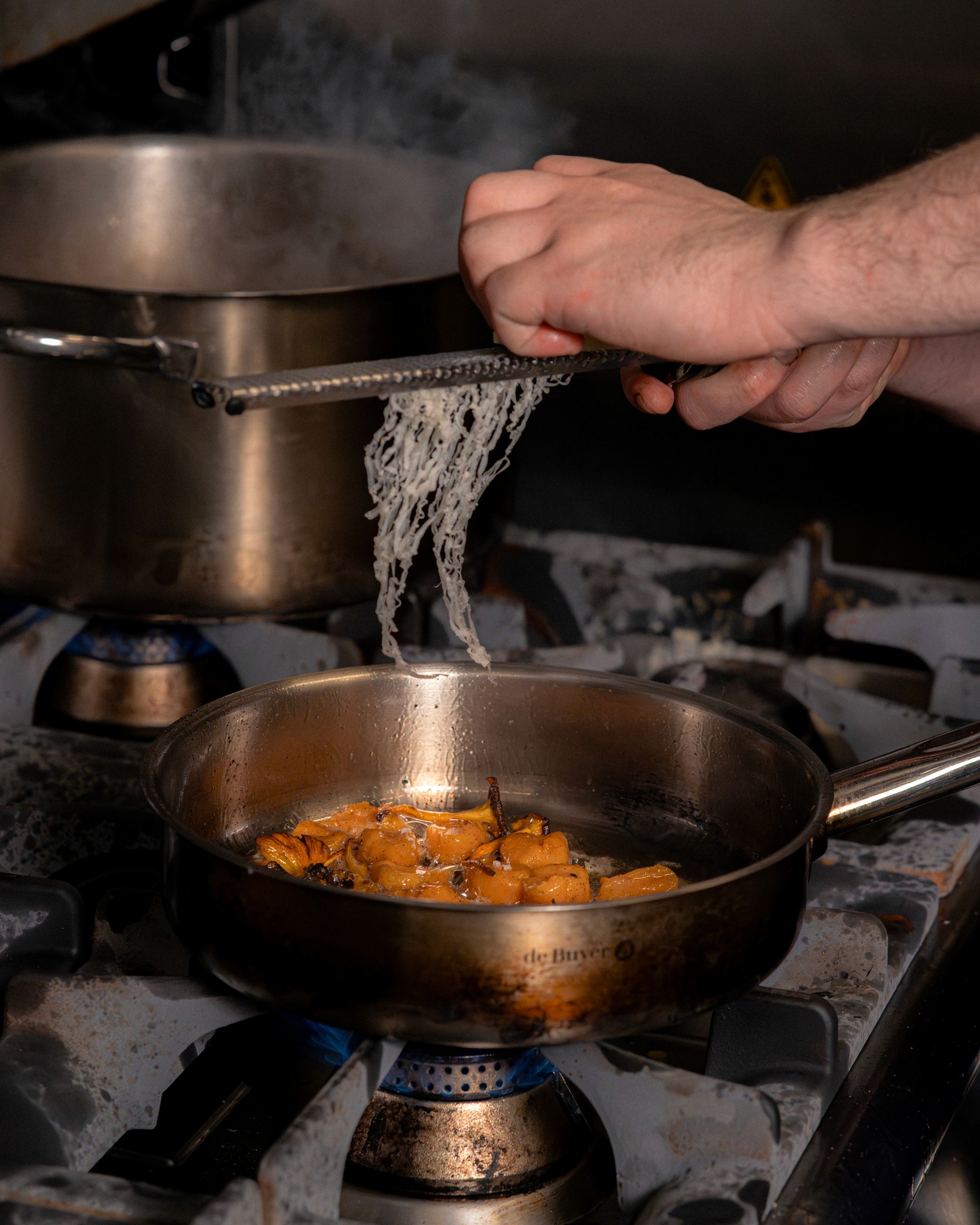 Préparation de pâtes fraîches en cuisine, égouttées au-dessus d’une casserole chaude, montrant le savoir-faire artisanal et la cuisine maison du restaurant.