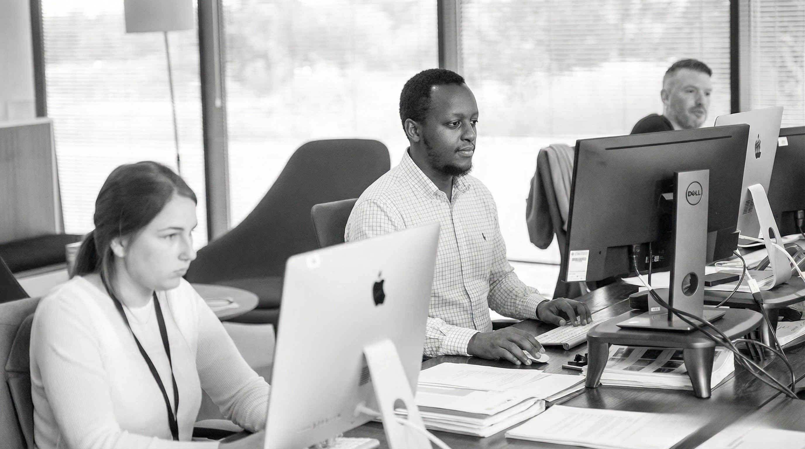 Team of three employees having a meeting at a table in a bright modern office.
