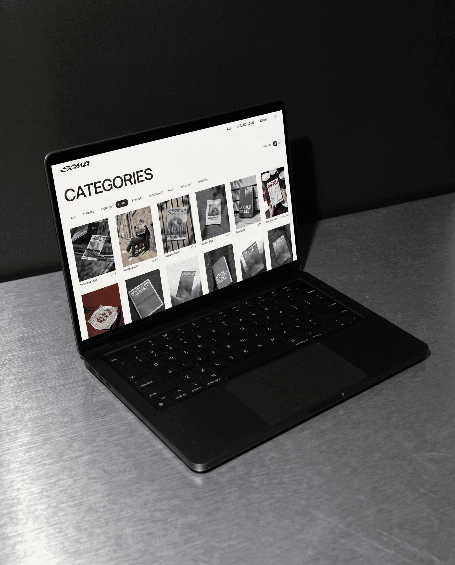 MacBook on a steel surface displaying Soma's Categories page with a grid of photorealistic mockups