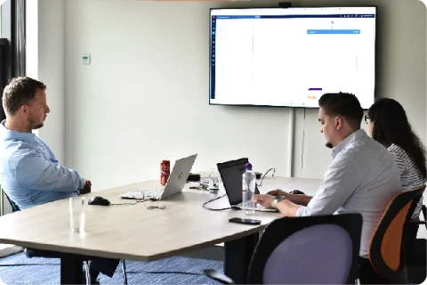 Exsion team members in a meeting room reviewing software on a screen
