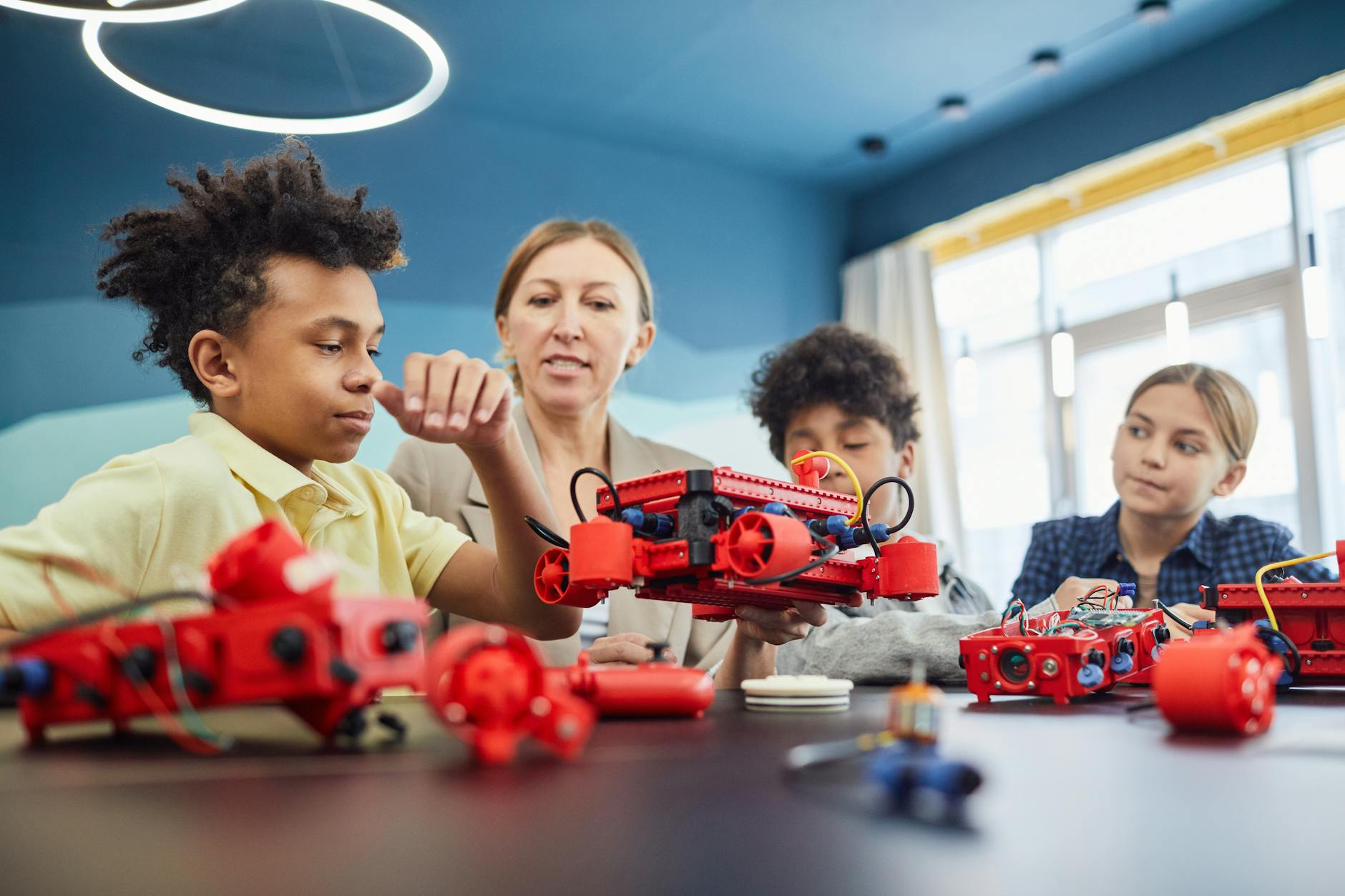 Close-up of a student's hands assembling a robotics kit while following a tutorial at online middle schools.