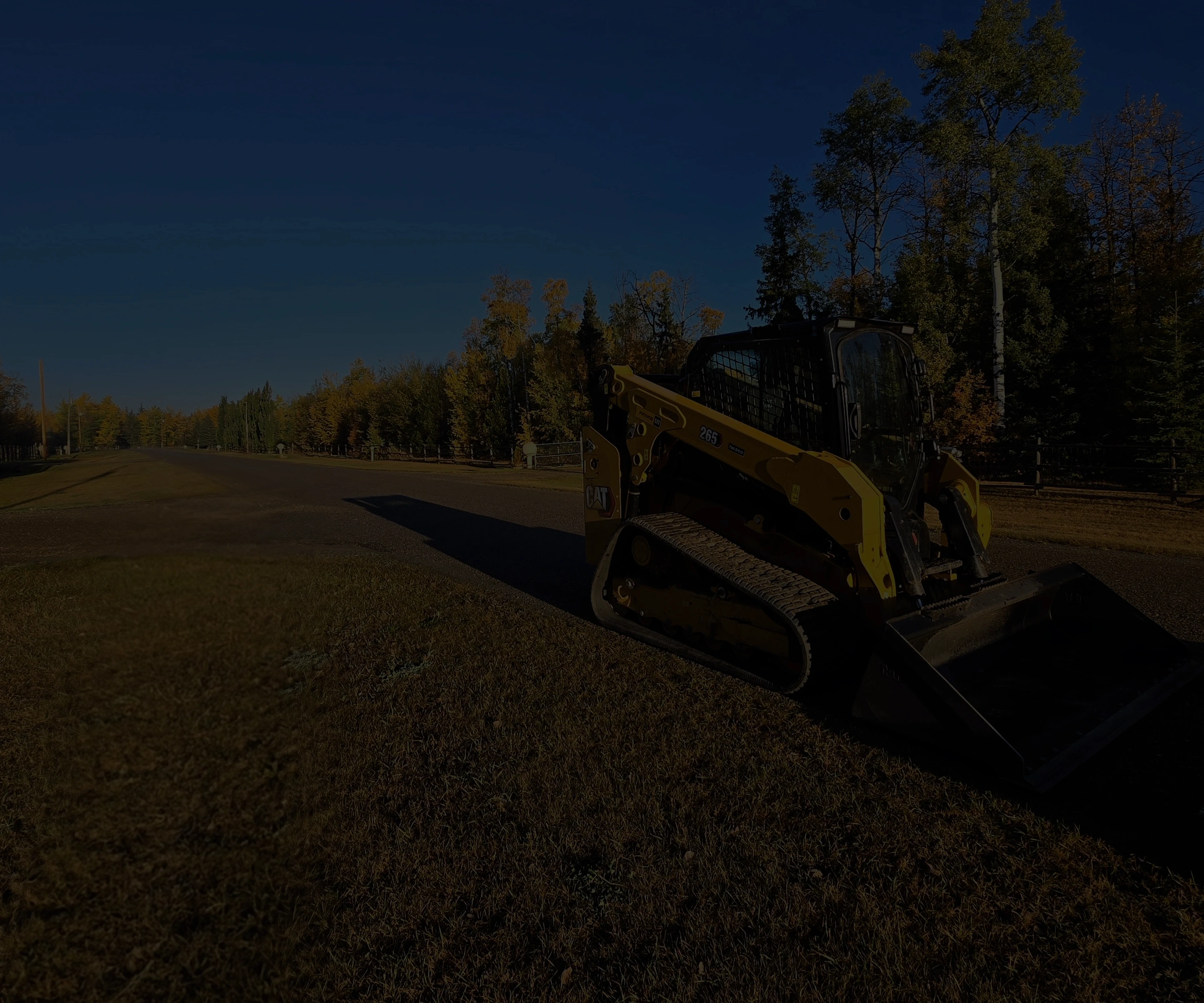 Skid steer sit on a county orad in parkland county