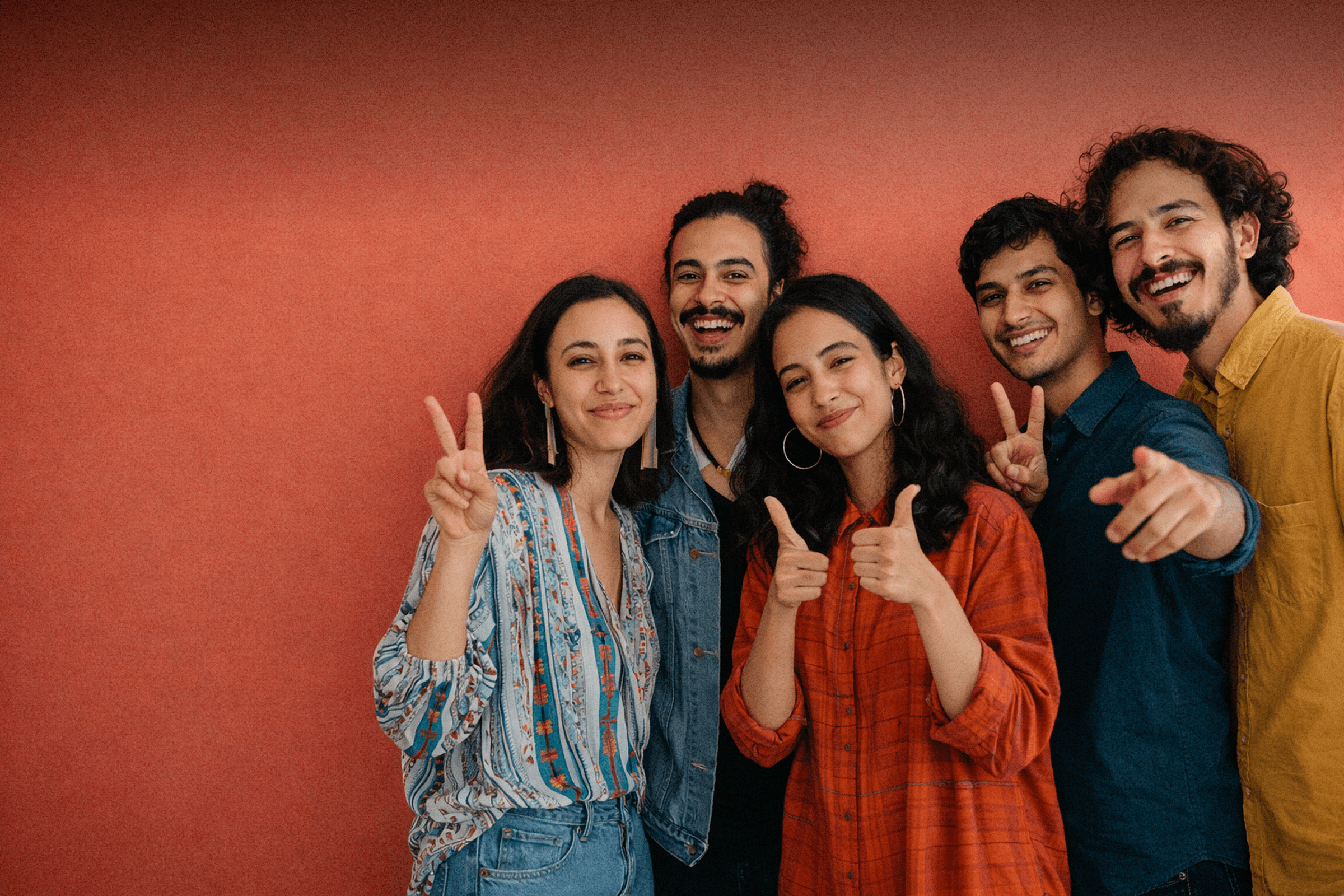 A cheerful group of young individuals showing thumbs up, symbolizing approval and camaraderie among friends.