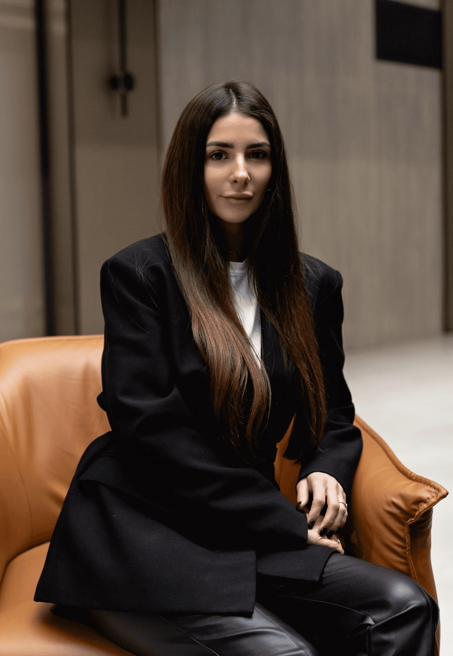 Casual studio portrait of a bearded man with curly hair in a white shirt, arms crossed, on a light gray background.