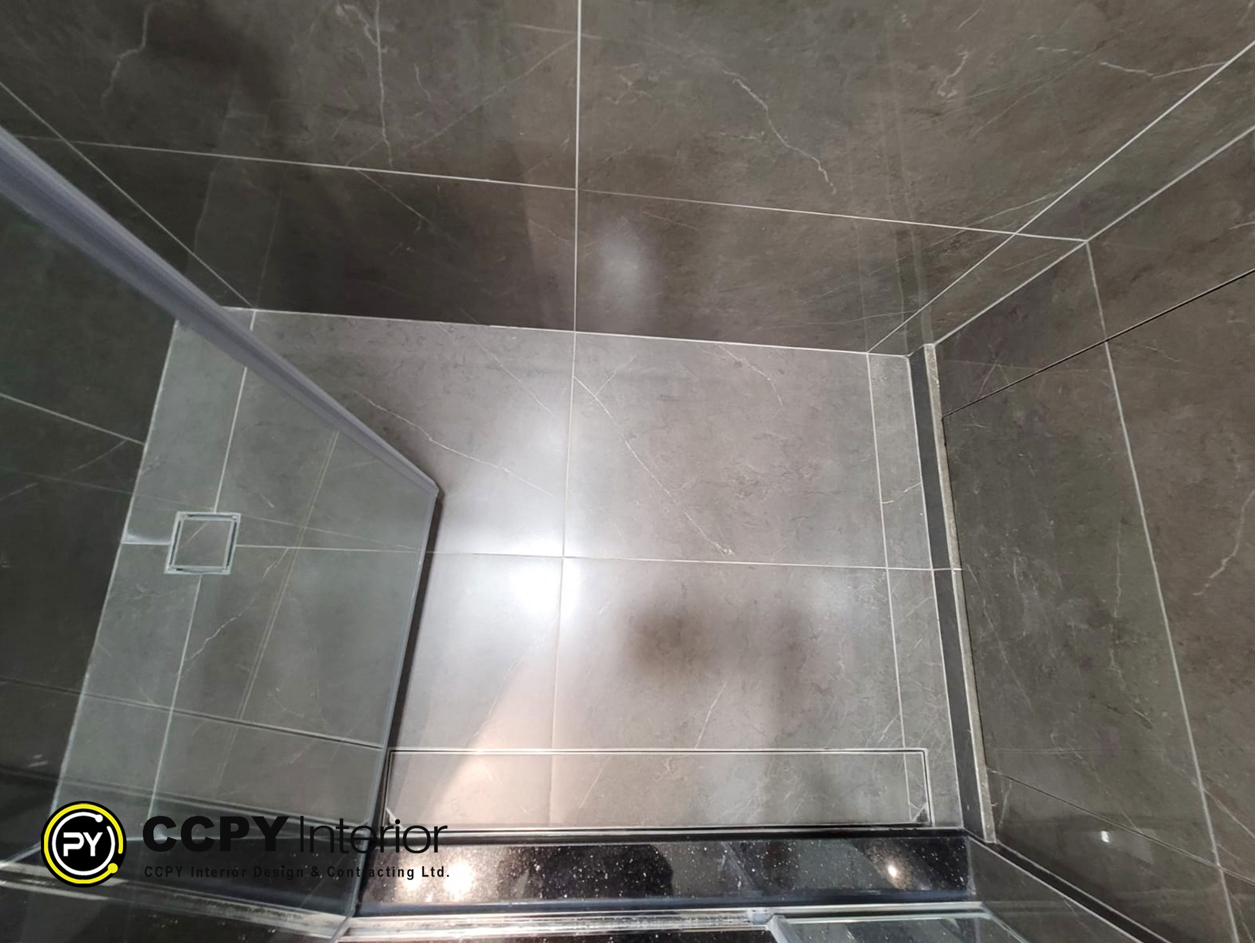 The shower is tiled with large-format porcelain tiles featuring a marble-effect design, commonly chosen for a modern look