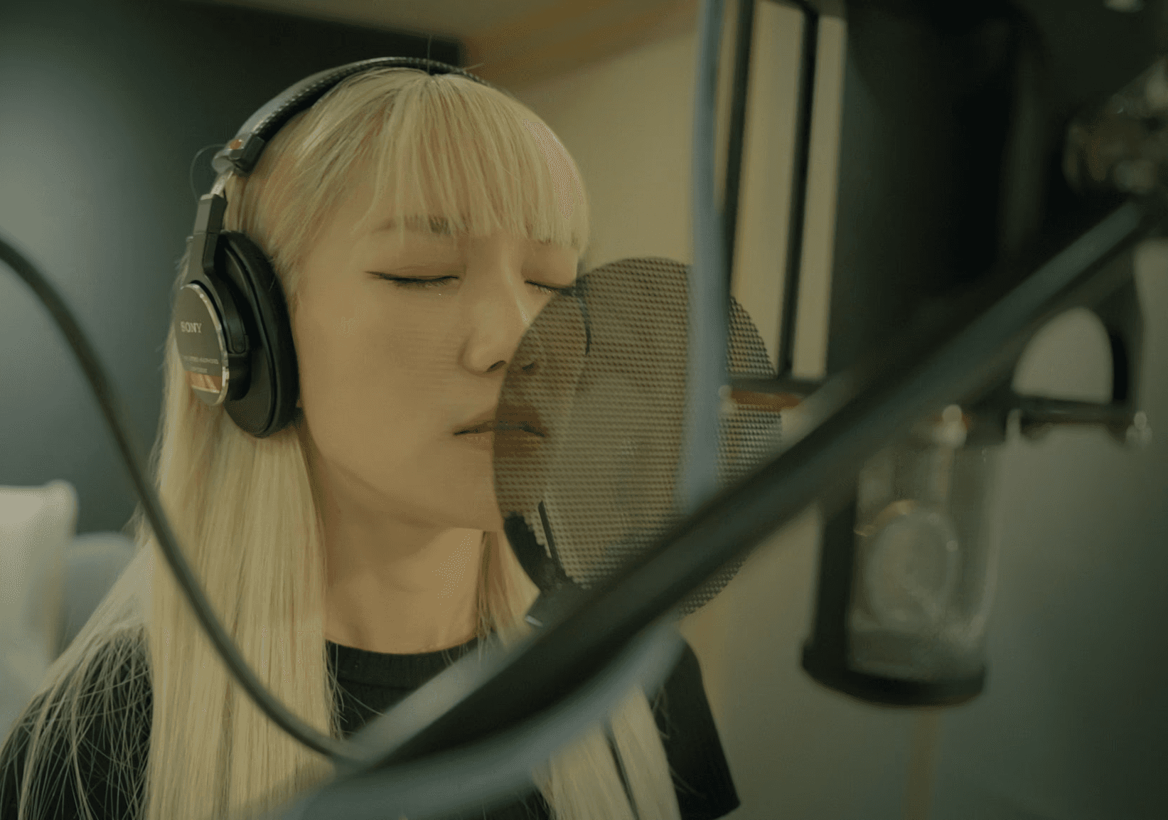 Film clapperboard in focus with glowing orange background, misty street, and silhouettes of people and lights; conveys mystery and anticipation.