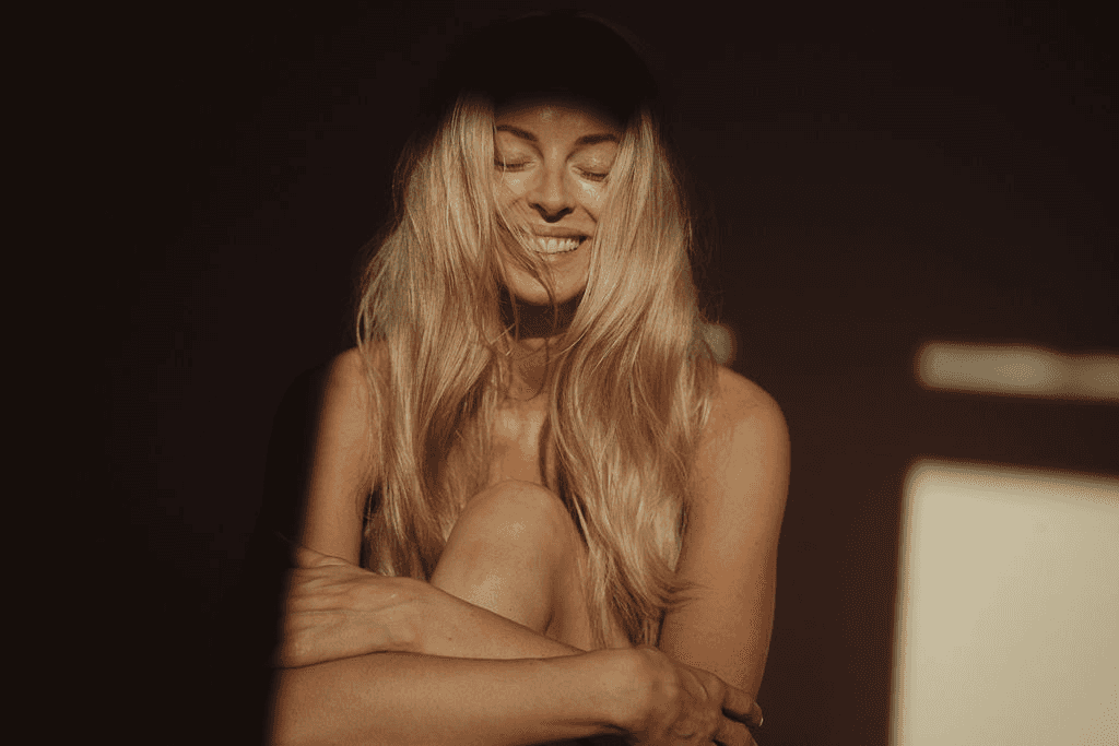 Woman smiling with eyes closed embracing self-love while healing intimacy issues