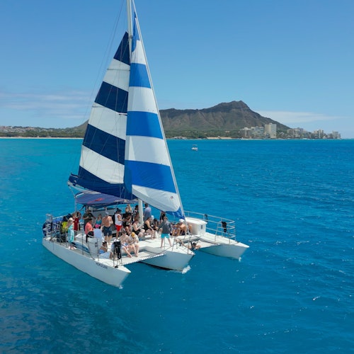 帆船双体船 Hokulani 载着游客，从威基基出发巡航，背景是钻石山。