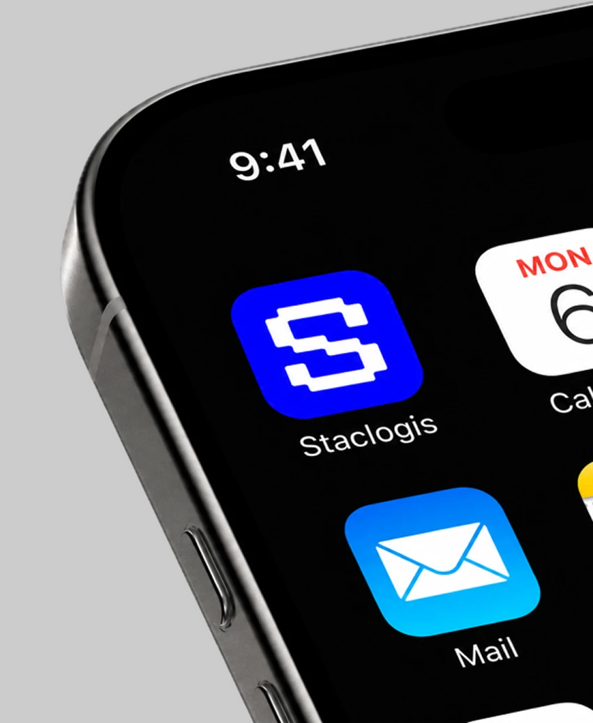 Close-up of a phone home screen showing the blue Staclogis app icon with the pixel "S" next to the Calendar and Mail apps.