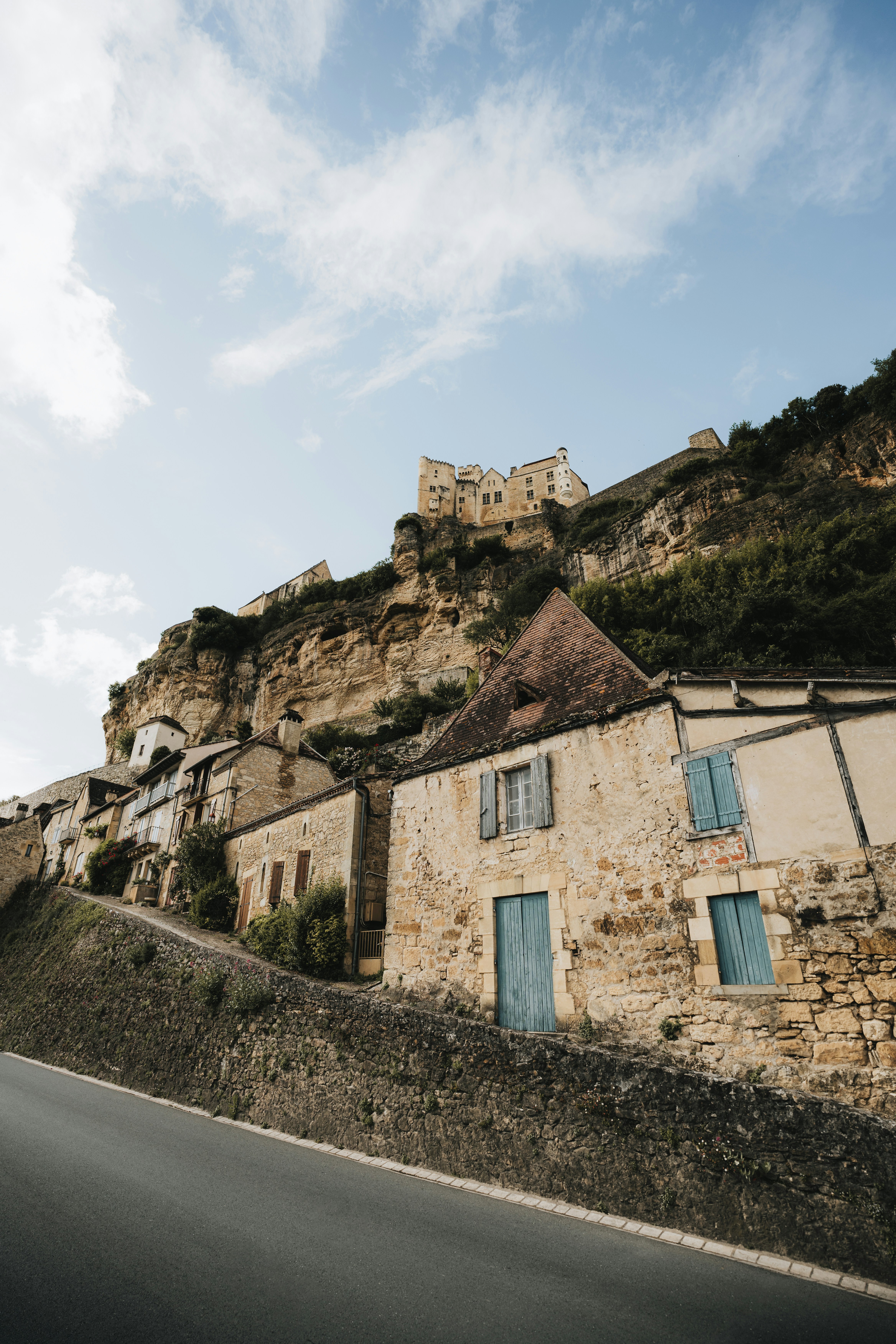 Medieval stone village on a cliffside with a castle above.
