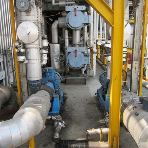 Industrial machinery with blue pumps, insulated pipes, and metal framework. Production equipment.