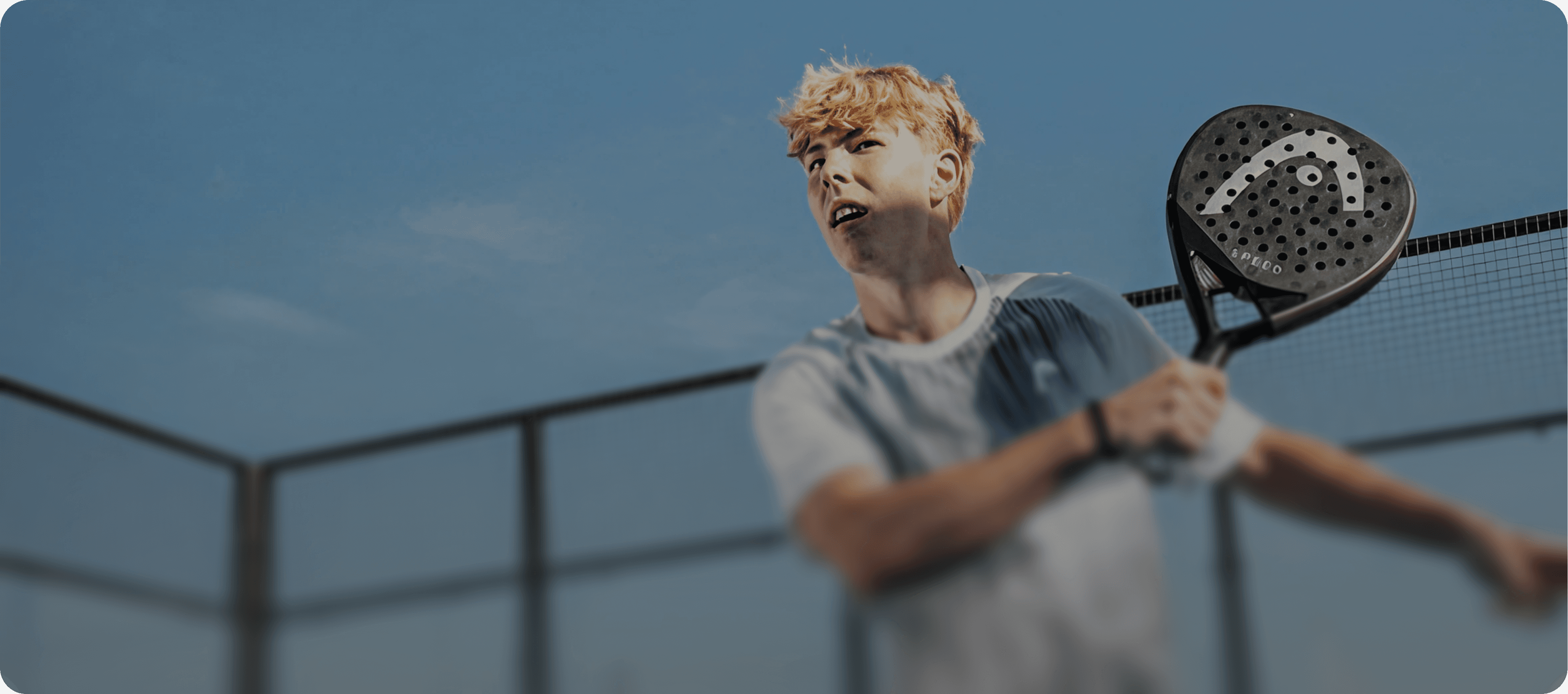 Young boy playing padel on a court, holding a paddle and hitting the ball.