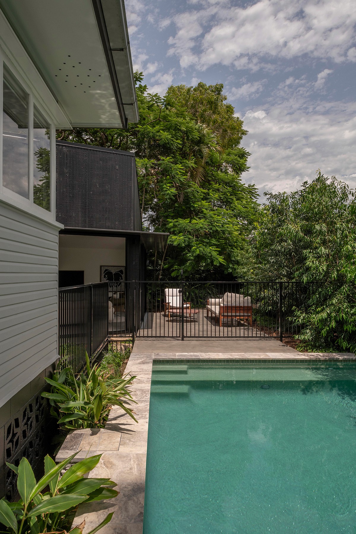 Pool and courtyard at Toohey Forest House with original dwelling, contemporary pavilion, and landscaped garden setting.