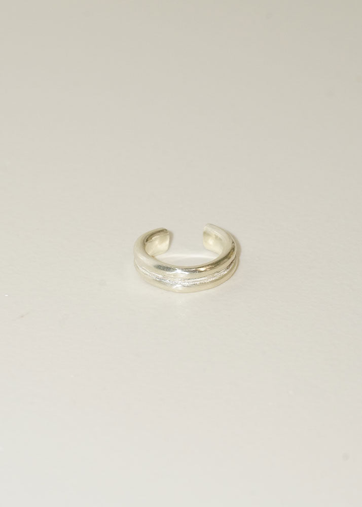 Silver open toe ring on a light beige background