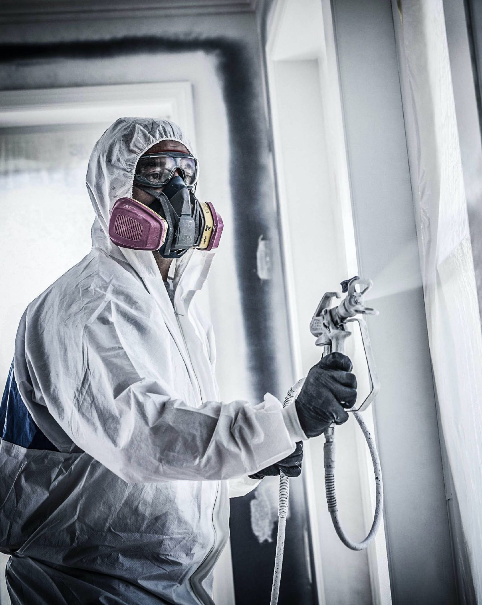 professional wearing safety gear paints room 