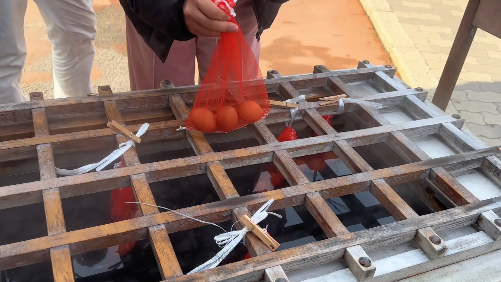 Visitors lowering a net of eggs into the hot spring boiling pit at Kinosaki.