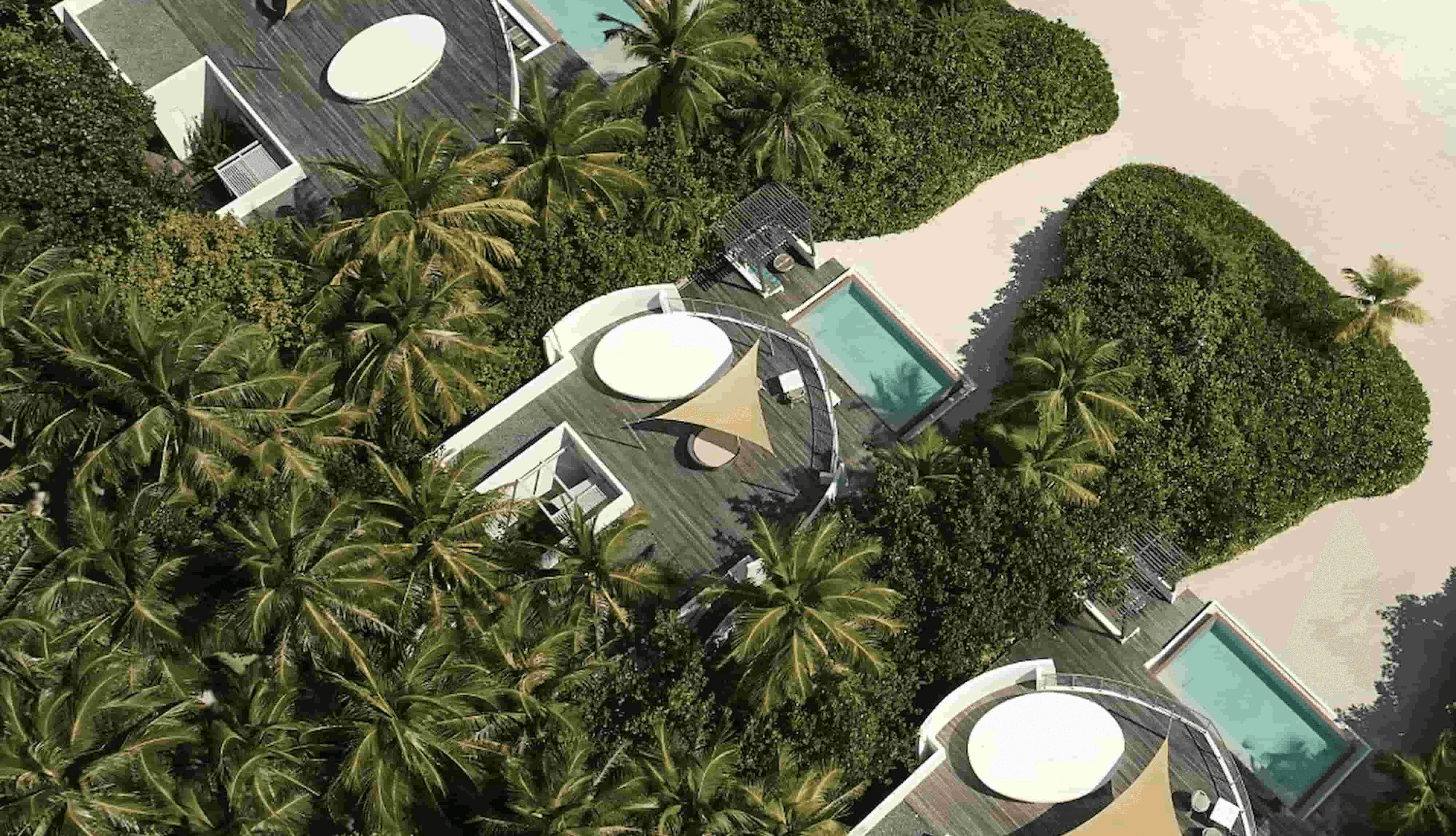 An aerial view of the villas in Jumeirah. The area has wide areas of sand with lush greens and modern, luxury housing.