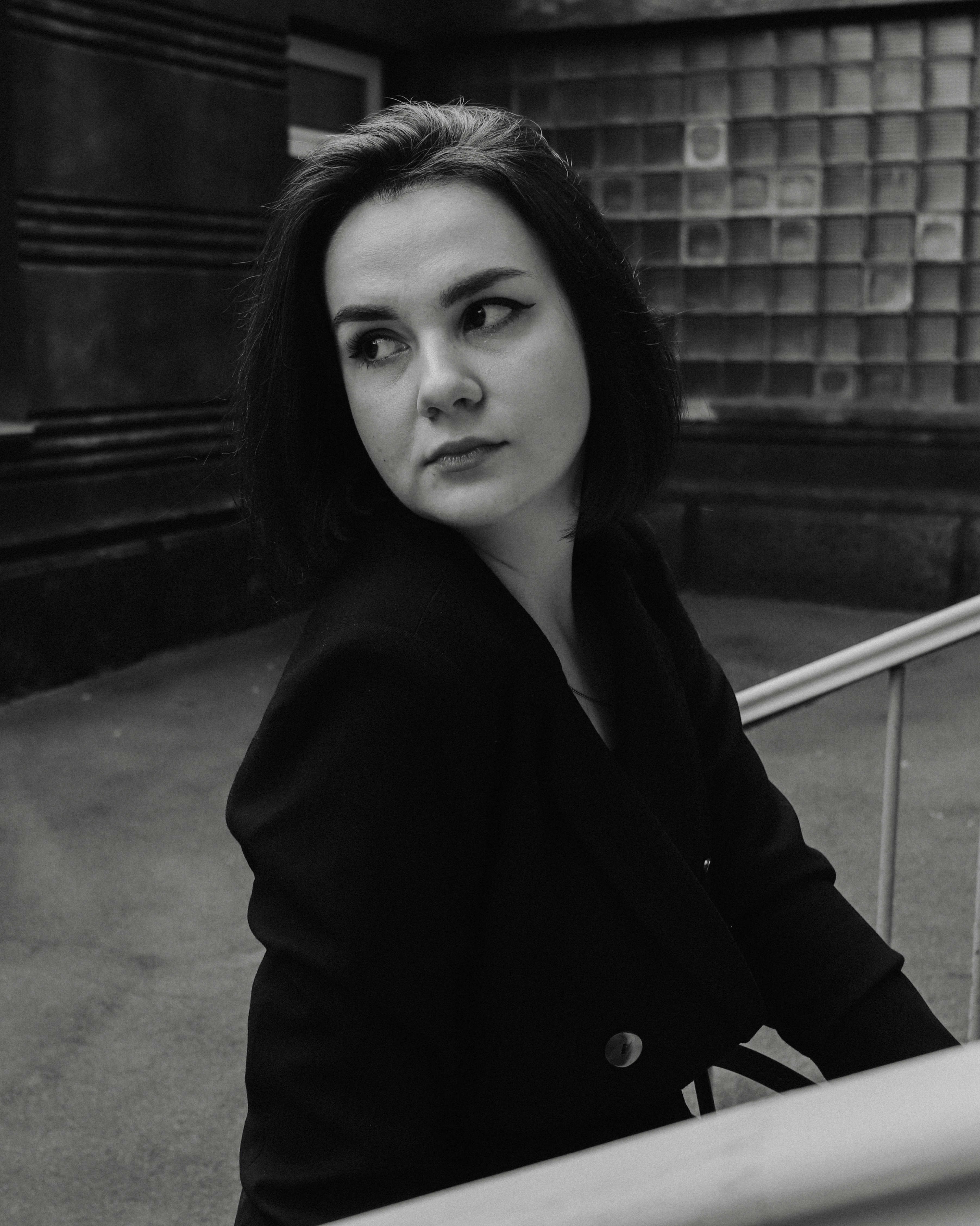 a black and white photo of a woman leaning on a railing