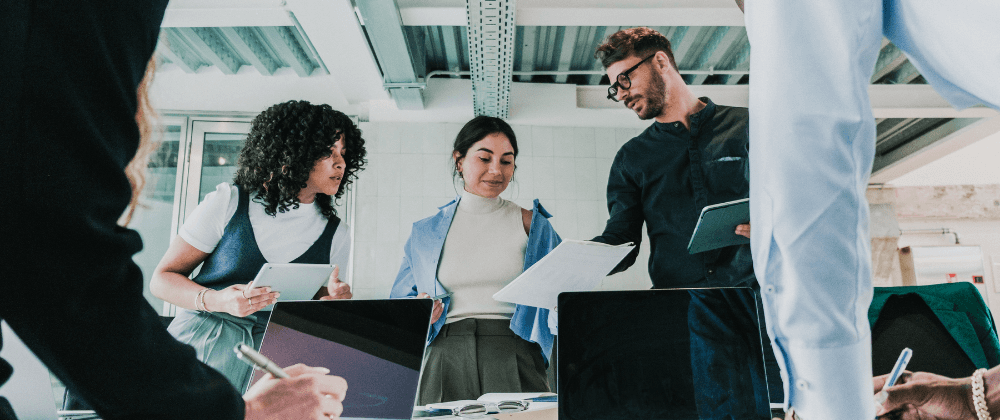Three teammates in a working room with others