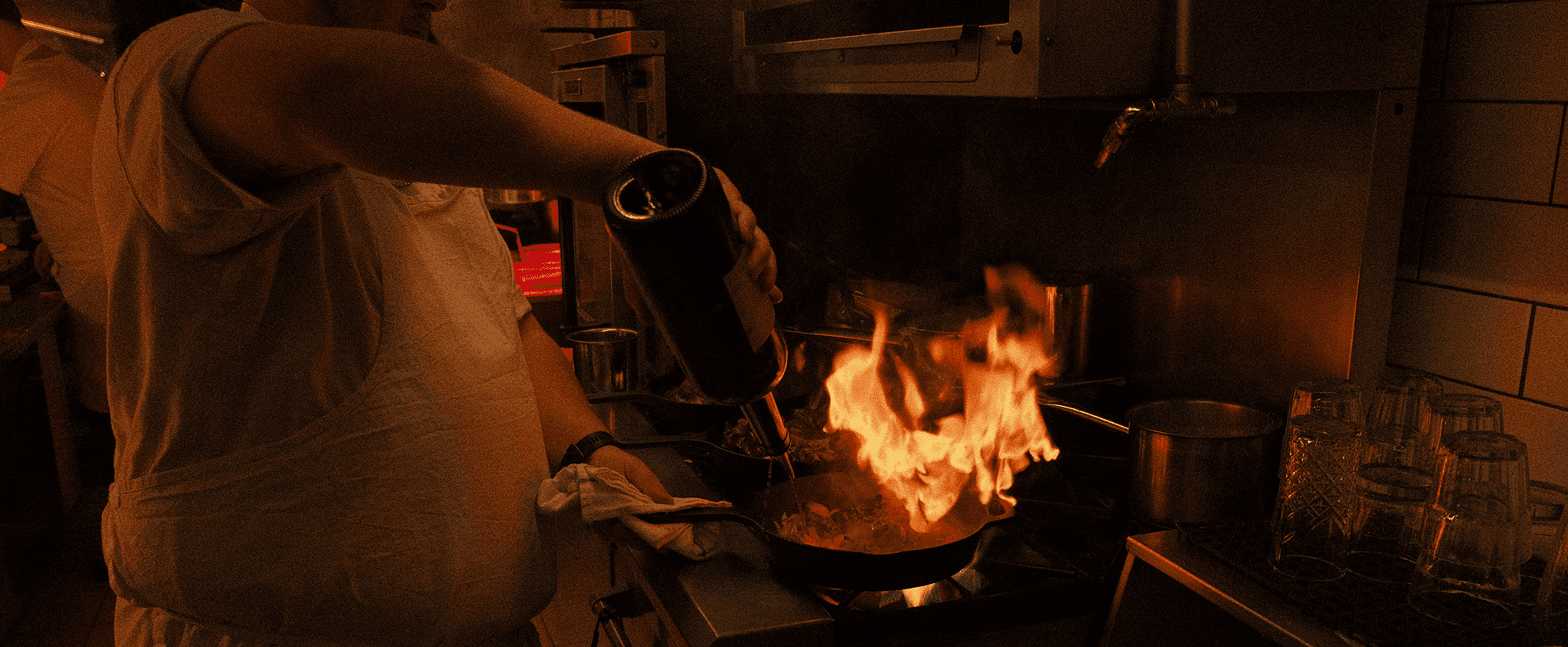 Un chef dans la cuisine du Ambre fais flamber un plat.