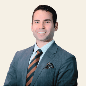 Headshot of Yuri Eliezer, smiling in a gray suit with a striped tie and pocket square.