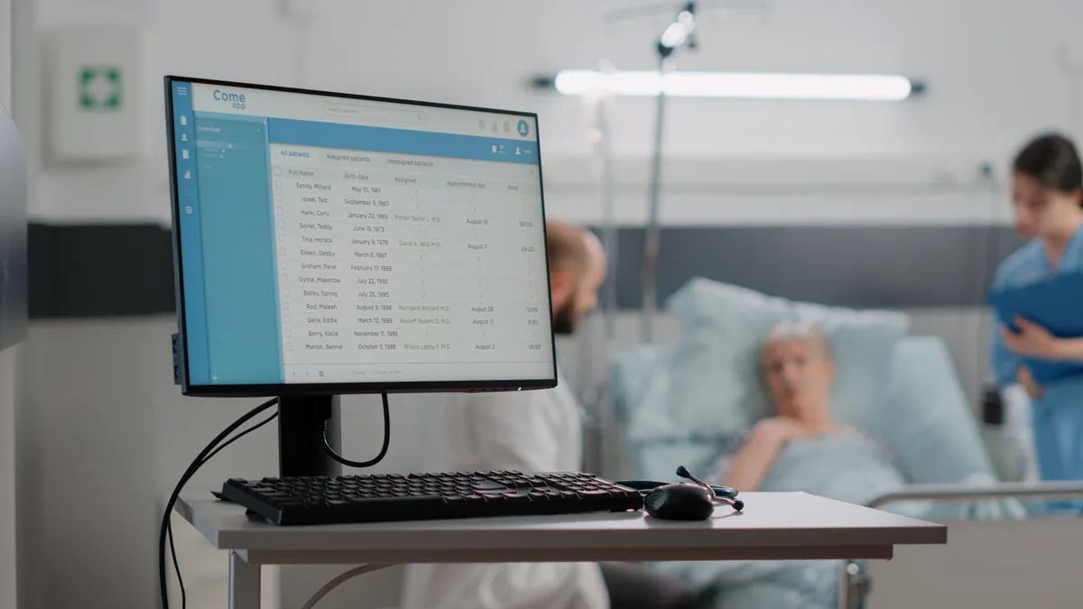 Screen showing patient records beside a hospital bed