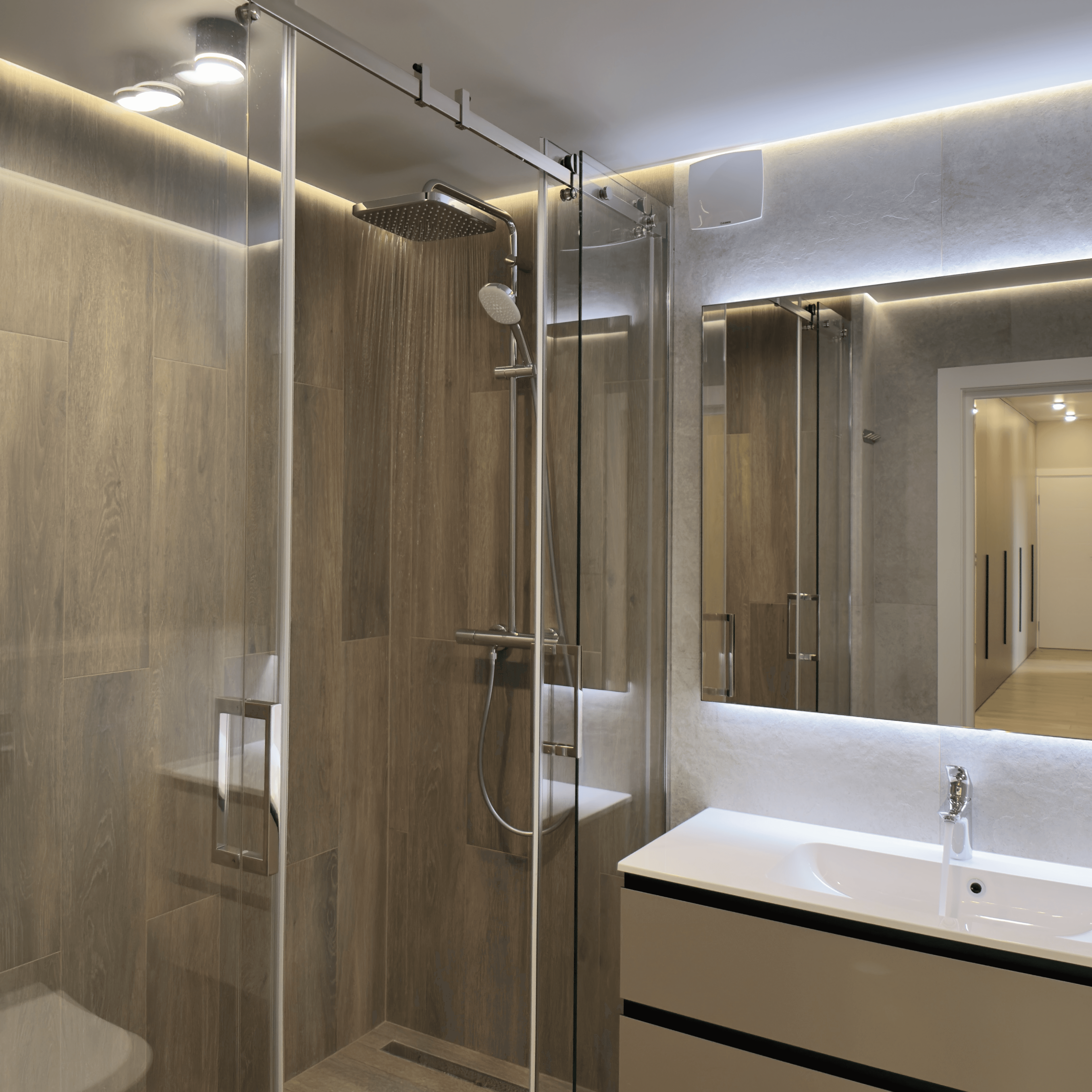 Сучасна ванна кімната з душовою кабіною, великим дзеркалом і меблями у світлих тонах