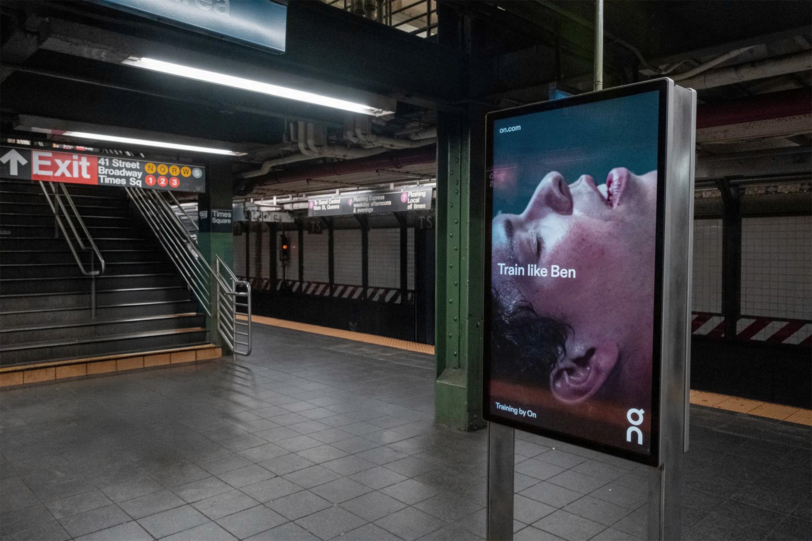 A digital billboard in a busy New York City subway station showcases a dramatic close-up of an athlete's face, mid-exertion, for the "Training like Ben" campaign by On Running. The high-impact out-of-home (OOH) advertising demonstrates the studio’s ability to execute global brand storytelling and large-scale digital marketing assets that capture attention in high-traffic urban environments.