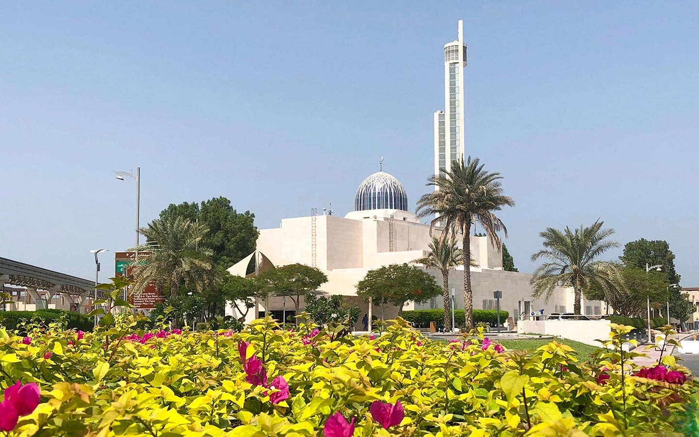 A contemporary mosque with a blue dome and tall minaret in the lush green, landscaped surroundings of Palm Jumeirah.