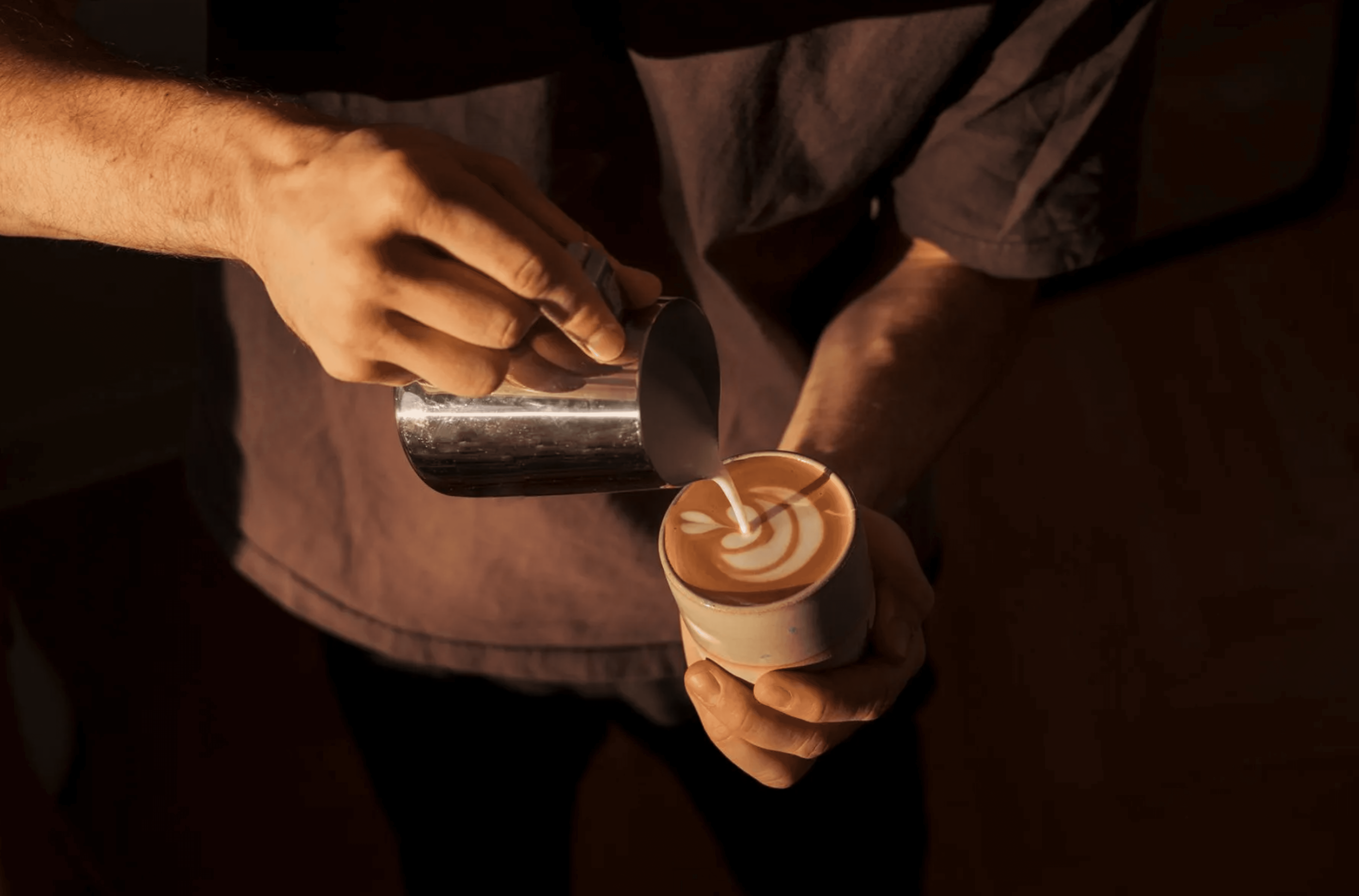 Barista gracefully making latte art in a to-go coffee cup