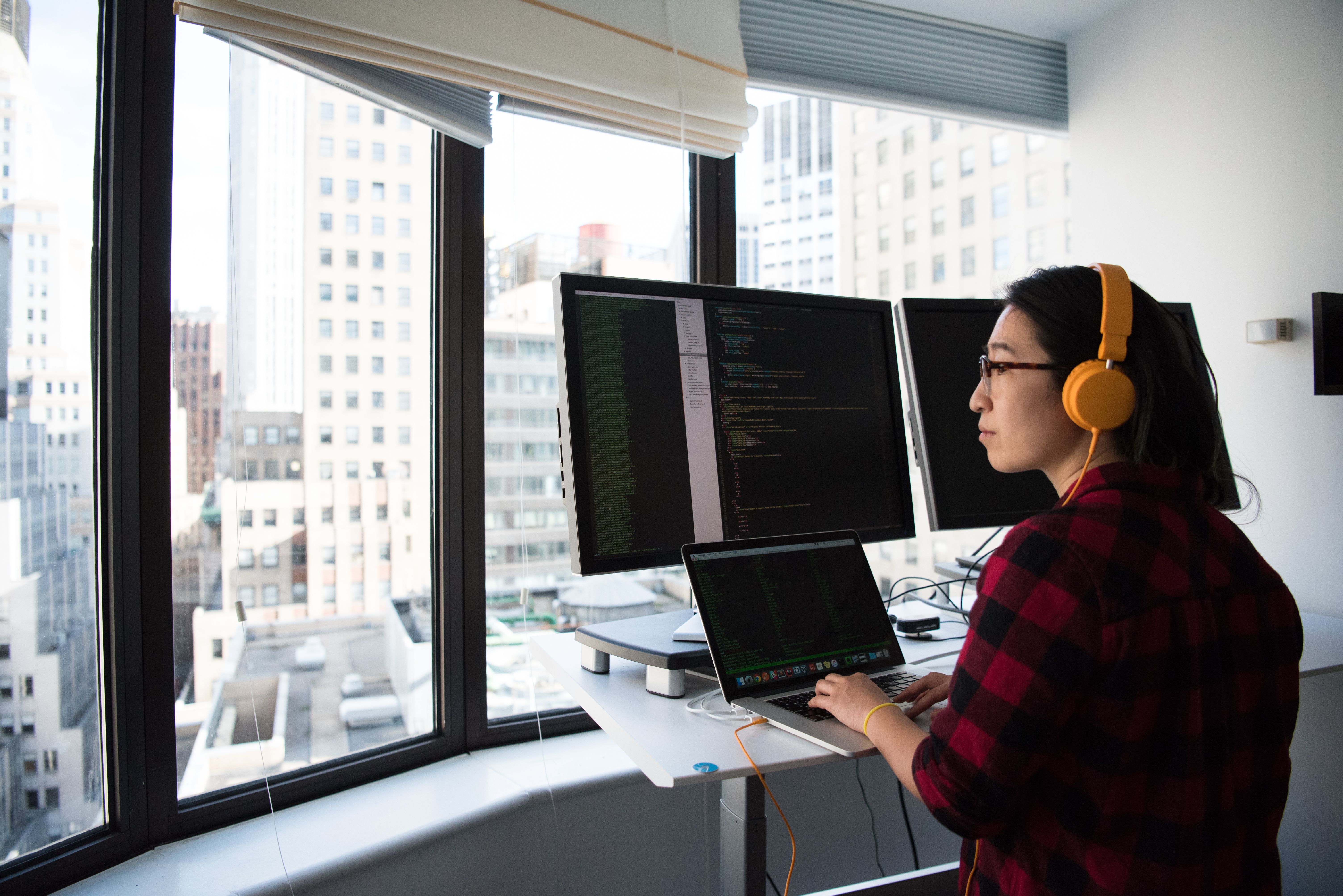 a-businesswoman-coding-at-a-standing-desk-with-city-views-through-large-windows, - christina-morillo (pexels)