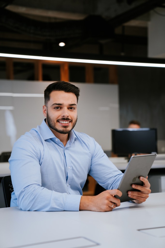 Sócios analisando gráficos de rendimento e lucro no computador, sorrindo com os resultados da economia tributária.