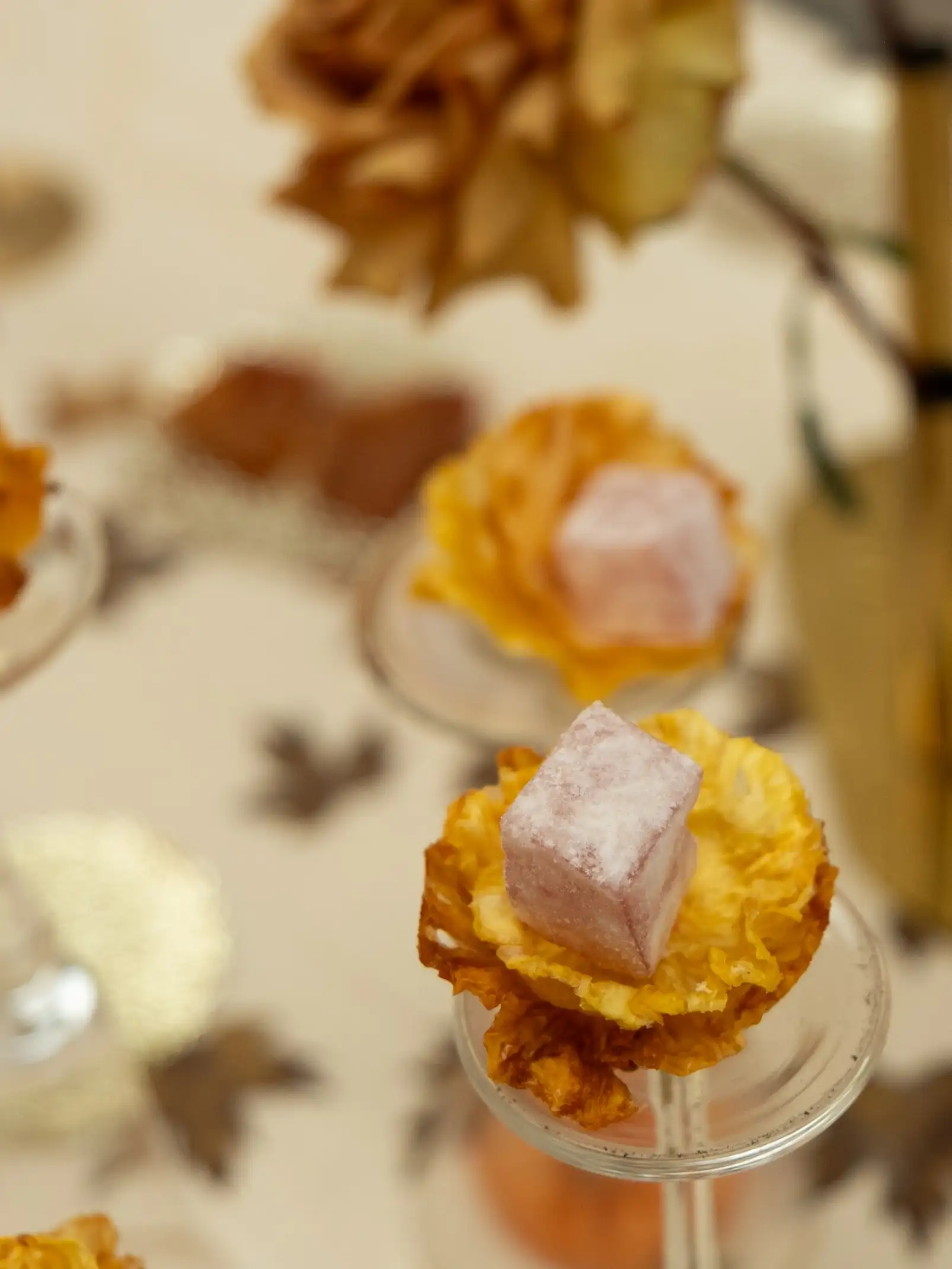 Detalle de mesa decorativa con pétalos secos y dulces artesanales para evento sensorial, resaltando texturas y tonos otoñales.