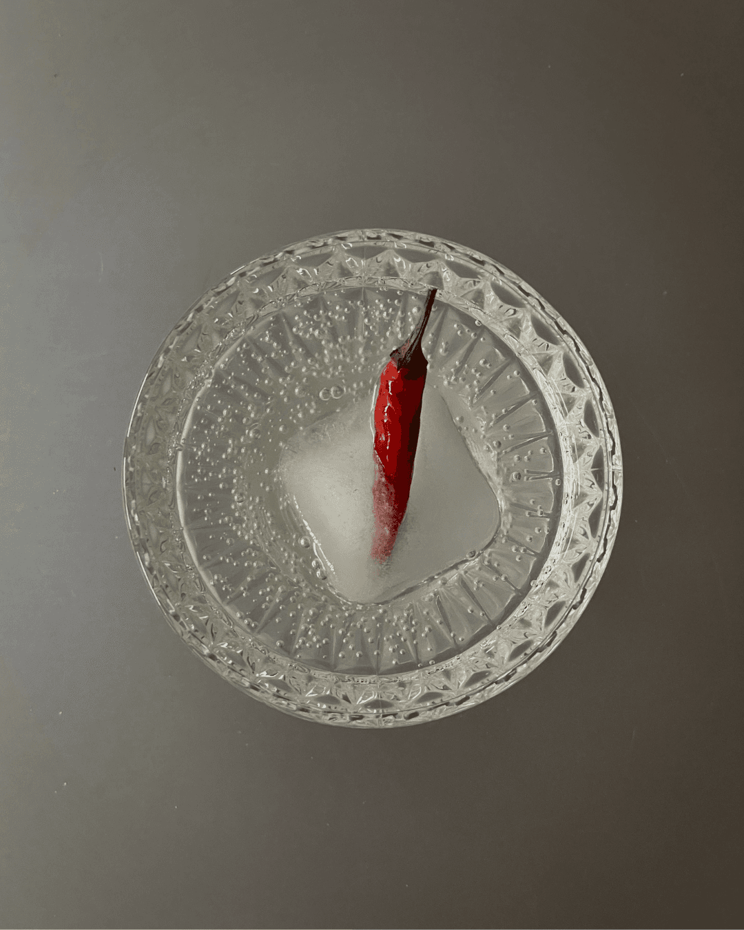 close-up of mysa served in a crystal coupe glass with a chili and square ice cube