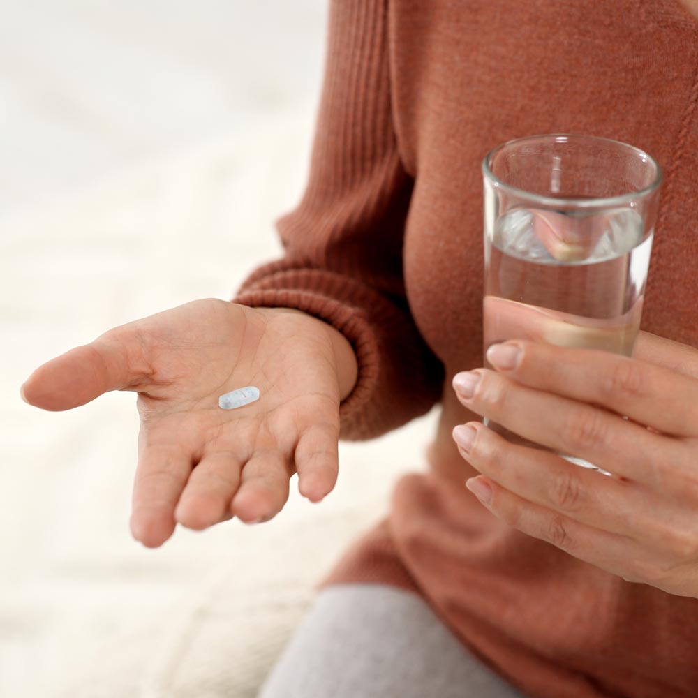 Woman holding pill and glass of water