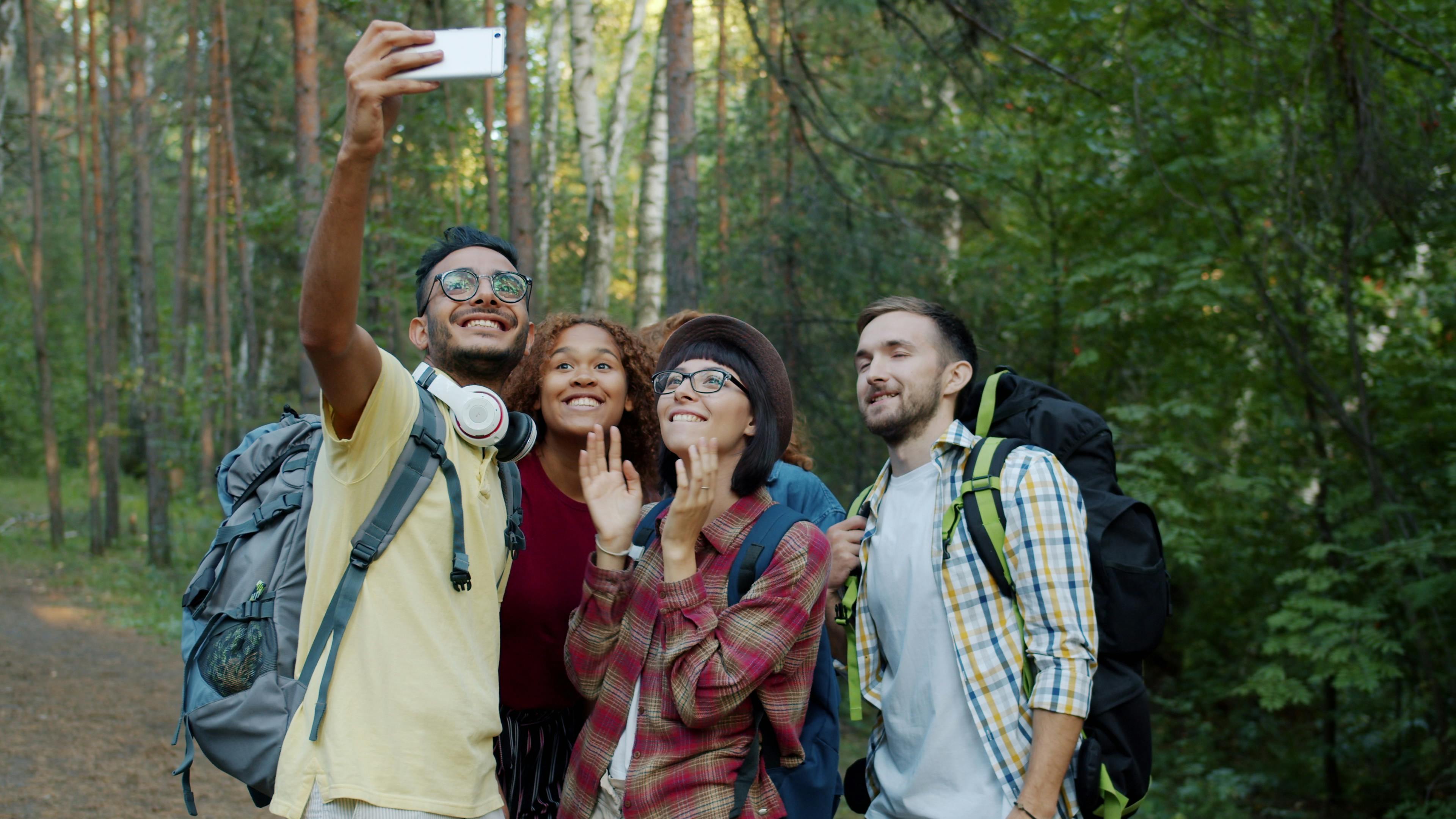 A diverse group of friends taking a selfie while hiking a lush, green forest trail in Metro Vancouver
