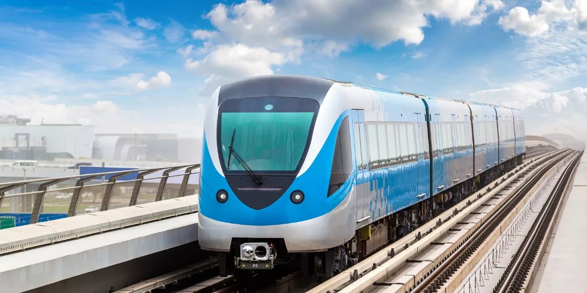 A man stands while two people sit at a table in an office setting, smiling and engaged in conversation. The mood is friendly and collaborative.