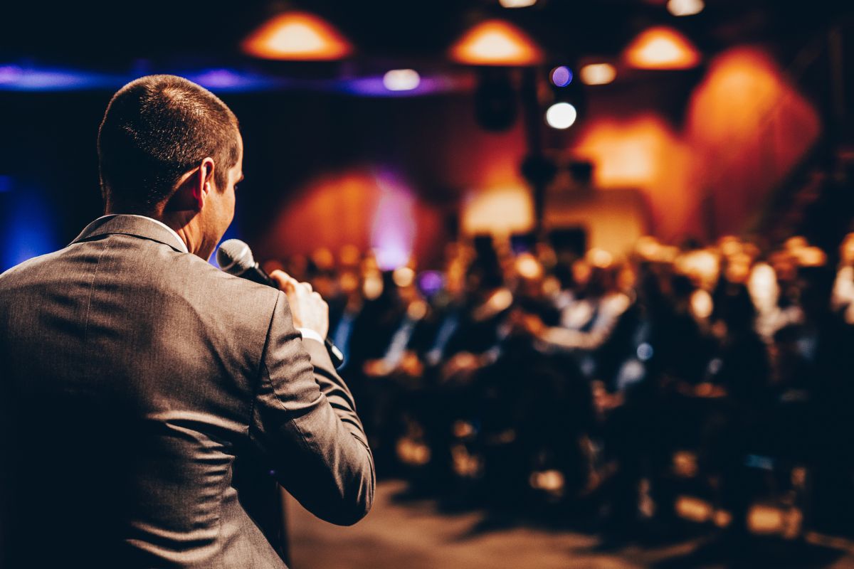 Gentleman speaking on a microphone at a business conference.