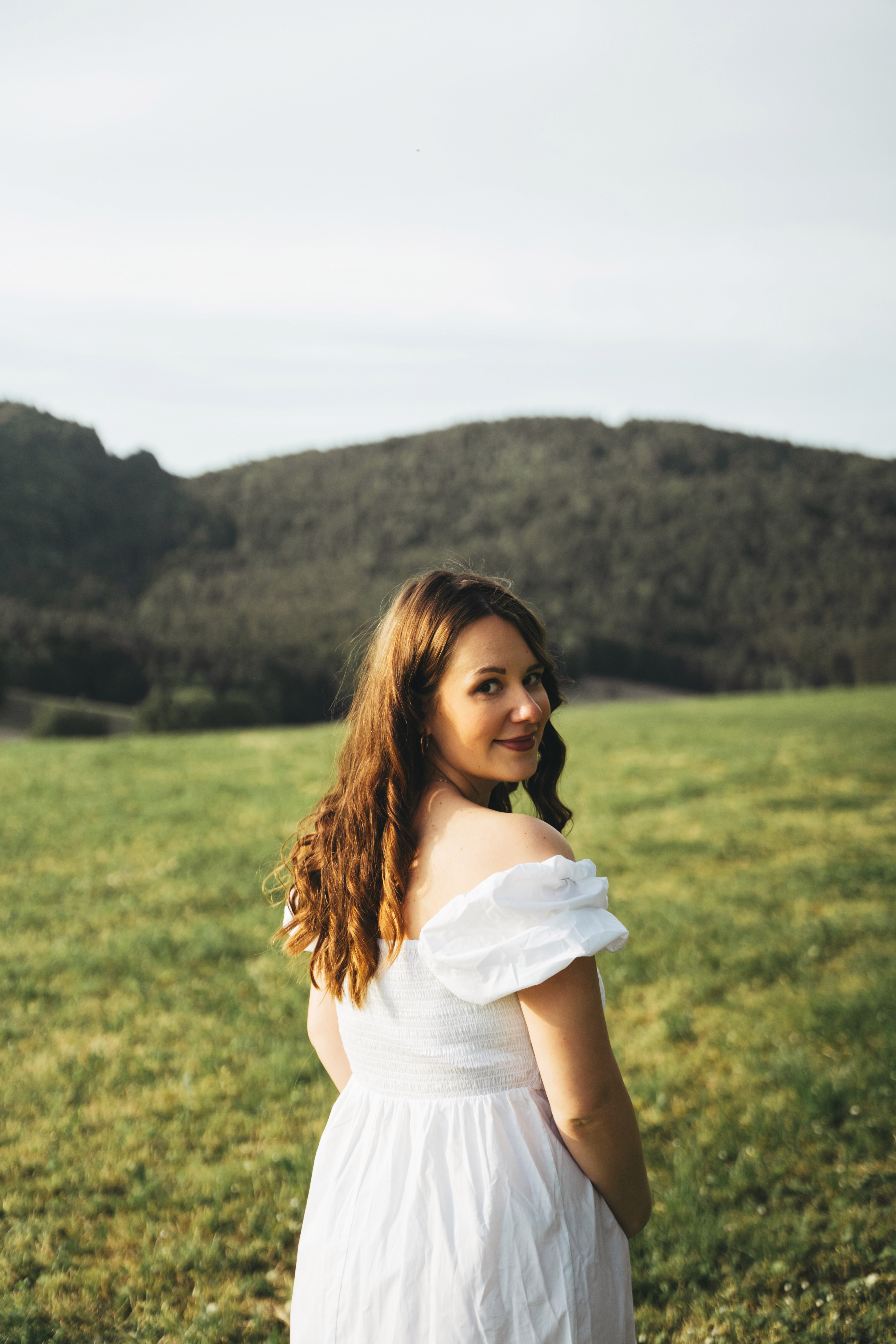 Natürliches Schwangerschaftsporträt in Bogen – schwangere Frau blickt lächelnd in die Kamera.