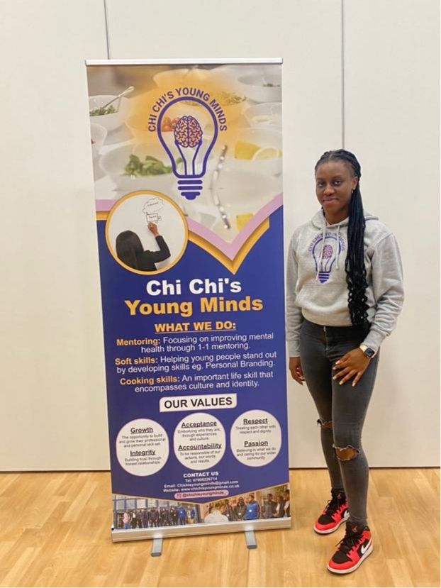 Women standing next to ChiChi Young Mind's purple and yellow roller banner. 